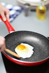 Female hands with fried egg on frying pan and wooden blade, closeup