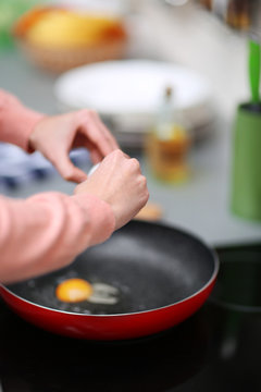 Female hands fried egg in frying pan, closeup
