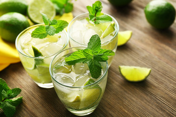 Mojito drink with lime and mint on wooden table