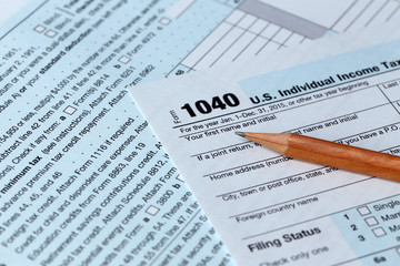 Obraz premium 1040 Individual Income Tax Return Form for 2015 year with a pencil to fill on the white desk, close up