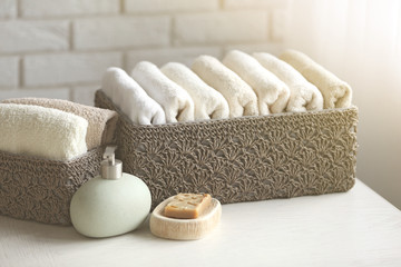 Wicker basket with towels inside and soap on wooden table background