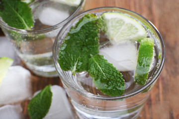 Fresh cocktail with mint, ice and lime on wooden table background