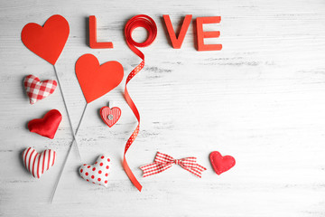 Valentine concept. Inscription love with hearts and card on wooden table background