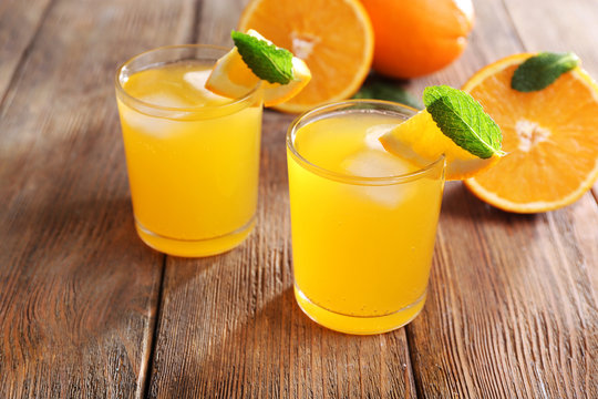 Two orange juices with ice and orange on wooden table background