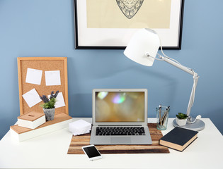 Workplace with laptop, mobile phone and table on blue wall background