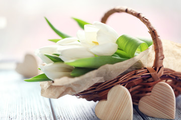 White tulips in a wicker basket on a light-blue table