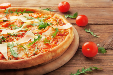 Margherita pizza with tomatoes, Parmesan and arugula on wooden background
