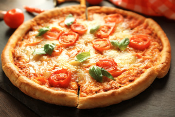 Margherita pizza with tomatoes on slate plate, close up