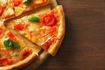 Sliced Margherita pizza on wooden background