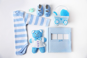 Baby clothes with toys and photo album on white background