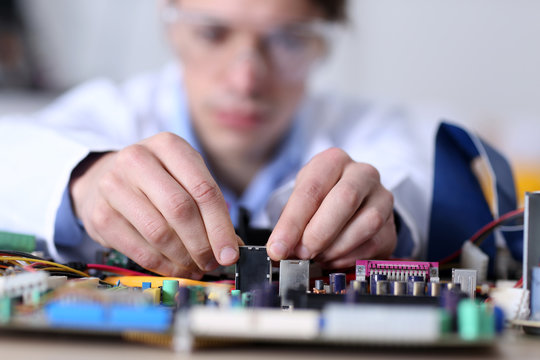 Young man in glasses repairing computer hardware in service center