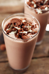 Glasses of chocolate milkshake on wooden table closeup