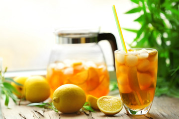 Fototapeta premium Glass and jar of iced tea with lemon on a windowsill