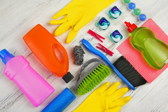 Cleaning set with tools and products on light wooden background