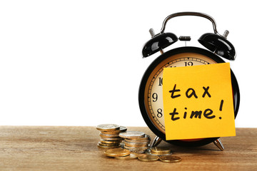 Tax time on alarm clock and coins on table