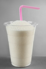Plastic glass full of sugar with straw on grey background