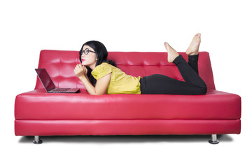 Female model with laptop daydreaming on sofa