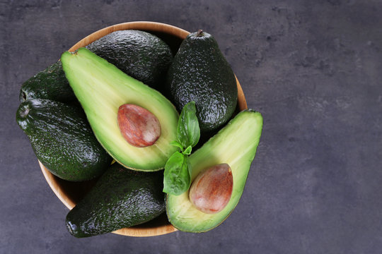Wooden plate full of avocados on a black background