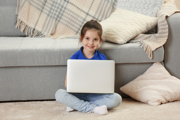 Naklejka premium Little girl using laptop on floor indoors