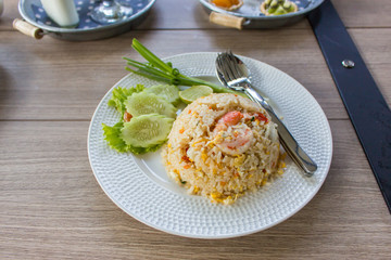 Shrimp fried rice is placed on a wooden table.