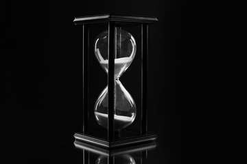 Black hourglass on black background, close up