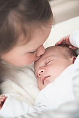 Big sister kissing her newborn brother