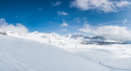Winter panorama with snow covered slopes and dramatic sky.
