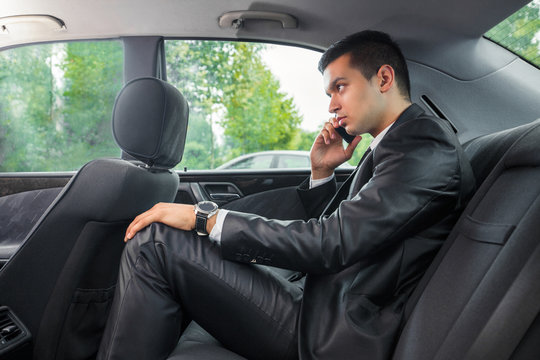 Young businessman talking on the phone while traveling to work by taxi