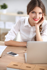 Attractive businesswoman sitting  on desk in the office