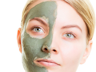 Woman in clay mud mask on face isolated on white.