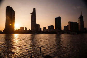Panorama of Ho Chi Minh viewed over Saigon river. Breathtaking dramatic light of sunset is highlighted by lens flare effect created by vintage photo equipment.