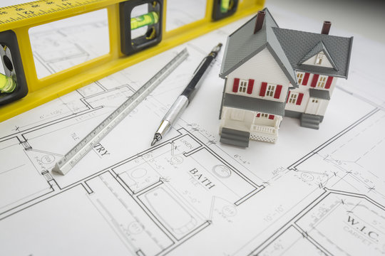 Model Home, Level, Pencil and Ruler Resting on House Plans
