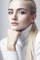 Close up of beautiful young blonde woman in white pullover. 
Professional beauty make-up and hair style.