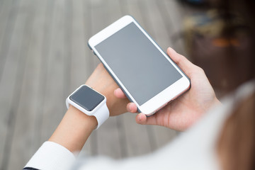 Woman using cellphone connecting with smartwatch