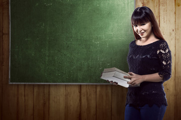 Asian student standing in front of blackboard background