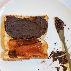 The close up of tasty bread toast and strawberry jam with chocolate spread on white plate.