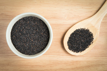 bowl of black sesame and a scoop of black sesame on a wooden bac