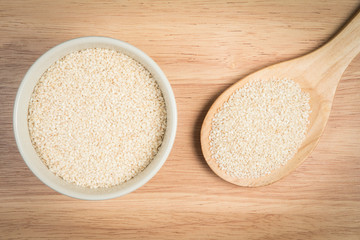 bowl of sesame and a scoop of sesame on a wooden background
