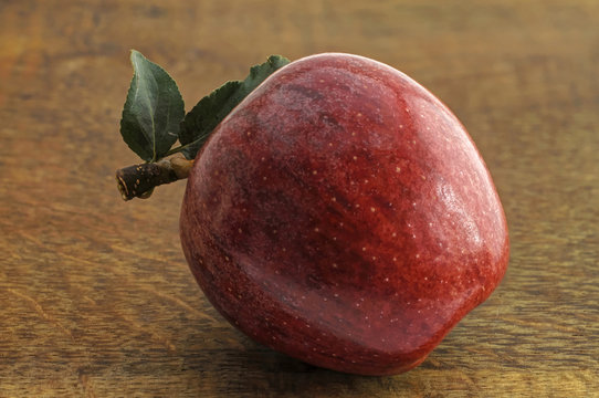 roter Apfle mit Blaettern auf Holztisch
