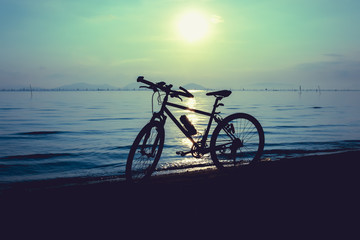 Silhouette of bicycle on the beach against colorful sunset