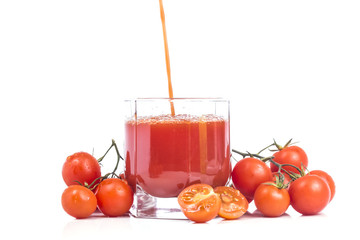 pouring a thick tomato juice in a glass with many small tomato