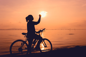 Silhouette of happy female celebrating with arm up towards the sun