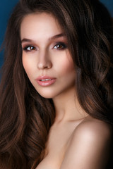 Fototapeta premium Beautiful Face Makeup close-up. Perfect Healthy Skin.Fashion Glamour Makeup. .Portrait of beautiful and sexy young woman over blue Background.Woman with beauty long brown hair - posing at studio