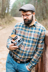 Fototapeta premium Young man bearded with film photocamera in the forest