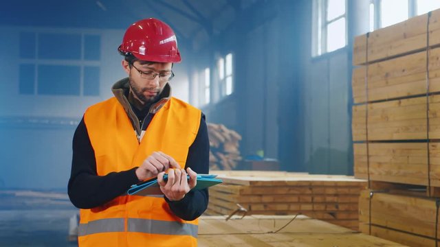 Warehouse worker in a helmet and uniform, the tablet uses