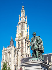 Naklejka na ściany i meble Statue of Peter Paul Rubens with Cathedral of Our Lady in Background in Antwerp, Belgium, under clear blue sky. The cathedral is the highest church in the Benelux with 123 m (404 ft) of height.