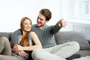 Fototapeta na wymiar Young happy couple on sofa watching TV 