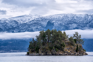 Small island beneath a mountain range deep in a Norwegian fjord