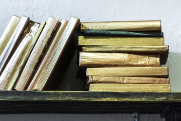 Stack of old books with golden covers on the shelf