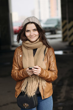Smiling beautiful woman holding phohe on roof of parking